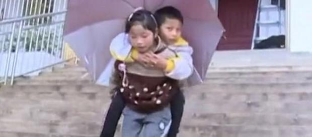O fetiță în vârstă de 9 ani din China, își duce în fiecare zi în spate la școală fratele - Foto: Daily Mail (© Wenshan Television Station) O fetiță în vârstă de 9 ani din China, își duce în fiecare zi în spate la școală fratele - Foto: Daily Mail (© Wenshan Television Station)