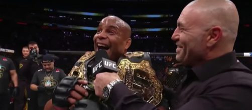 Daniel Cormier grins in excitement with his titles after retaining the UFC Heavyweight Title at UFC 230. - [UFC / YouTube screencap]