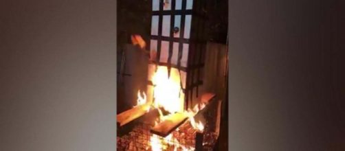 A cardboard effigy of Grenfell Tower bursts into flames. [Image @alexberesfordTV/Twitter]