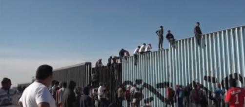 Migrants scale border fence near Tijuana, Mexico. - [AP Archive / YouTube screencap]