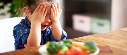 Una bambina davanti ad un piatto di verdure