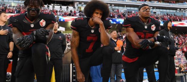 Kaepernick, en el medio, reticente a levantarse durante el himno Kaepernick, en el medio, reticente a levantarse durante el himno