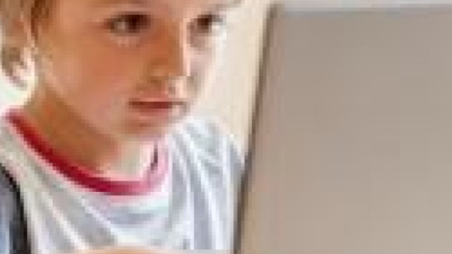 Foto di bambino al computer a rischio dipendenza dai social.