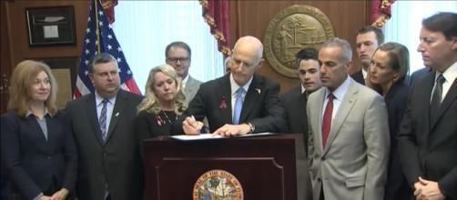 Florida Gov. Rick Scott signs gun restriction law. - [PBS NewsHour / YouTube screencap]