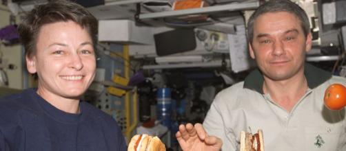 ISS astronauts eating a meal in the Service Module with tomato and hamburger floating (Image credit – NASA, Wikimedia Commons)