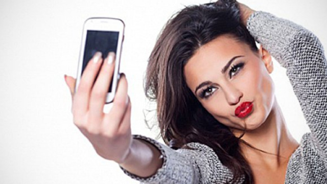 Una ragazza intenta a scattarsi un selfie.