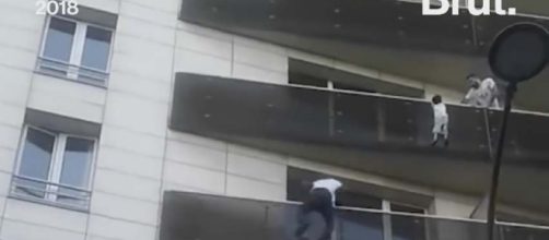 An undocumented migrant from Mali was a hero in Paris when he climbed a building to rescue a small child. [Image: Brut/YouTube]