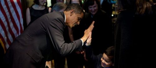 President Barack Obama high fives with a boy at a fundraiser for Bill Owens (Image courtesy - Pete Souza, Wikimedia Commons)
