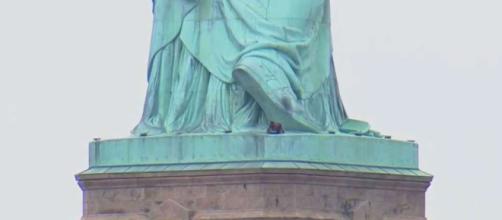 NUEVA YORK / Una mujer se sube a a la base de la Estatua de la Libertad como protesta