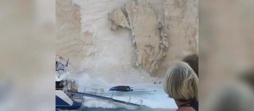 The moment tons of rock crashed down on a busy beach in Greece. [Image Guardian News/YouTube]
