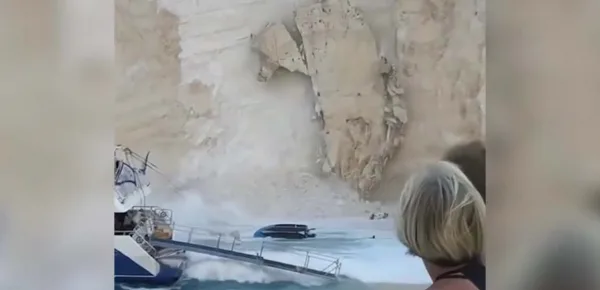 The moment tons of rock crashed down on a busy beach in Greece. [Image Guardian News/YouTube]