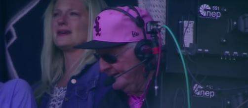 'Hawk' Harrelson calling a game between the Chicago Cubs and Chicago White Sox with his family near. [Image Source: MLB - YouTube]