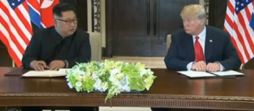 Donald Trump and Kim Jong-un sign document after summit. [Image source/ABC News (Australia) YouTube video]