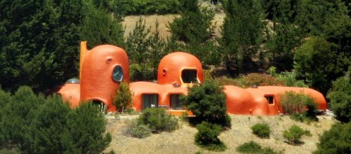 The Flintstone House, pictured here, has had a herd of massive dinosaurs added to it on on an astro turf lawn. [Image Sergei Krupnov/Wikimedia]