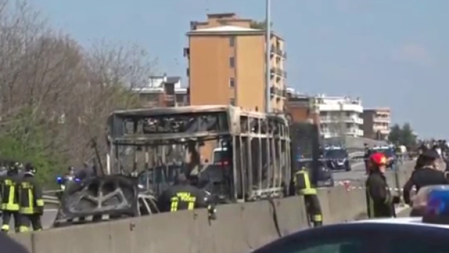 I resti dello scuolabus bruciato a San Donato Milanese: sarebbe Adam il vero autore della telefonata che ha allertato i carabinieri.