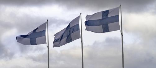 Three Finnish flags flying on poles. [Image via LTapsaH - Pixabay]