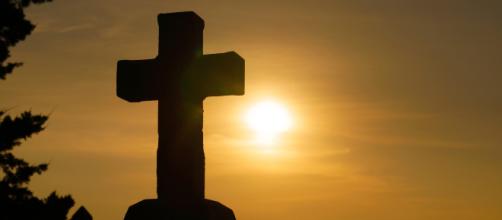 A Christian Cross with the sun in the background. [Image via sspiehs3 - Pixabay]