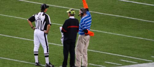 A ref is seen talking to television coordinators on the sidelines. [image source: Michael Holley- Wikimedia Commons]