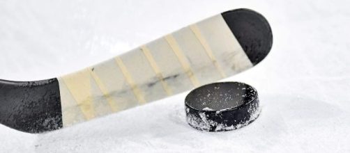 A hockey stick and puck on ice. [Image via soerli - Pixabay]