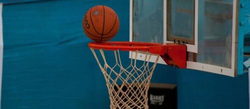 A basketball on the top of a rim. [Image credit - PDPics - Pixabay]