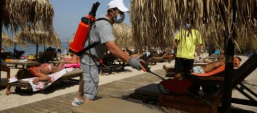 En Grecia, personal desinfecta las reposeras de las playas.