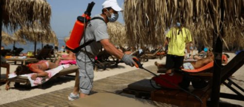 En Grecia, personal desinfecta las reposeras de las playas.