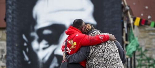 Due persone si stringono di fronte al murales dedicato a George Floyd.