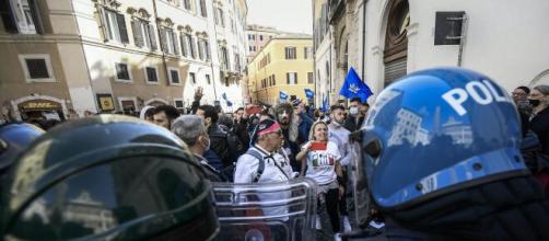 Roma, proteste per riaperture, un agente si toglie il casco tra gli applausi della folla.