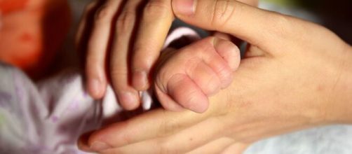 La mano di una madre stringe quella di un neonato (© Pixabay).