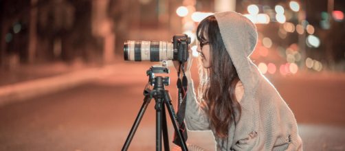 Ragazza pronta a scattare foto col teleobbiettivo - © Pixabay.