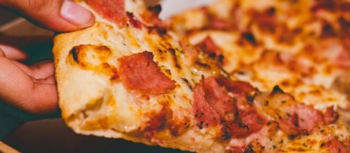 Una fetta di pizza che viene sollevata © Pexels