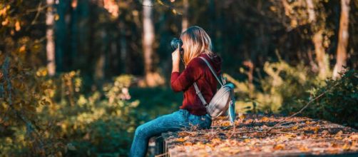 Ragazza che fotografa degli alberi © Pexels