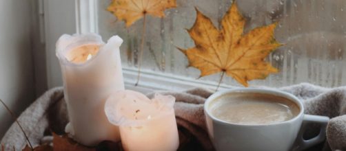 Tazza di caffé e latte con candele alla finestra- © Pexels