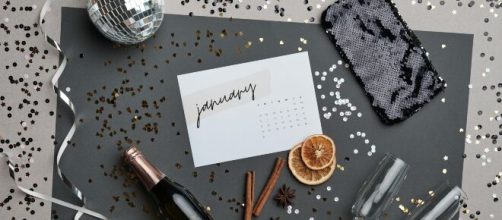 Calendario con gennaio, bottiglia e addobbi festivi - © Pexels.