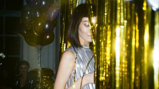 Ragazza nascosta da una tenda a una festa &copy; Pexels