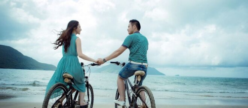 Una coppia che va in bici sulla spiaggia © Pixabay.