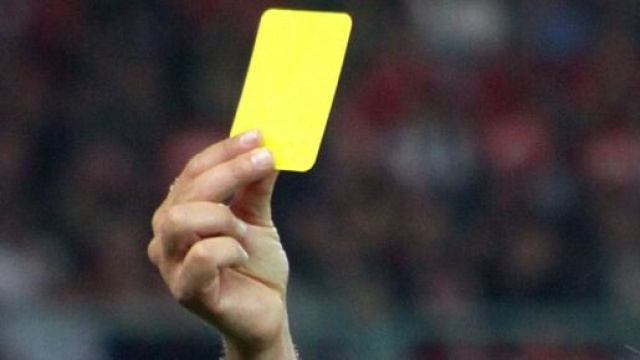 Arbitro di calcio che mostra un cartellino giallo &copy; Wikimedia Commons