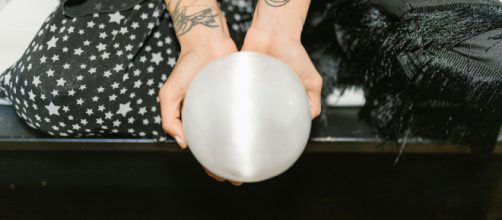 Mani con in mano una sfera di cristallo- ©Pexels