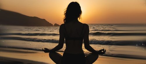 Figura femminile in meditazione sulla spiaggia al tramonto - © Pixabay.