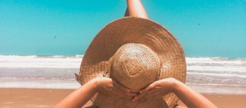 Donna con cappello in spiaggia © Pexels