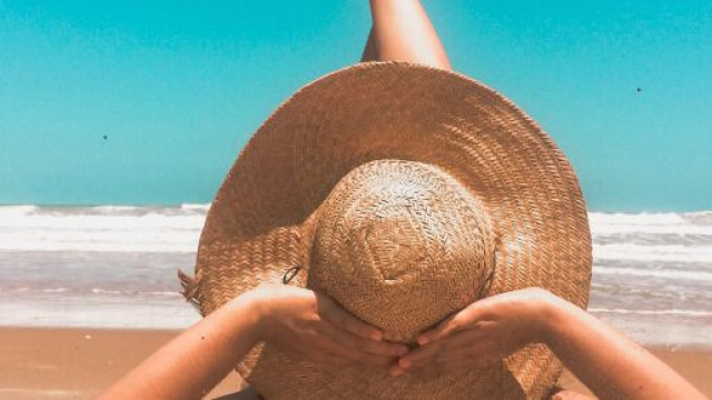 Donna con cappello in spiaggia &copy; Pexels