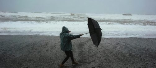 Uomo con ombrello e mare in tempesta - © Pexels.