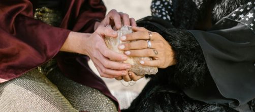 Mani di ragazze su una pietra divinatoria- ©Pexels.com