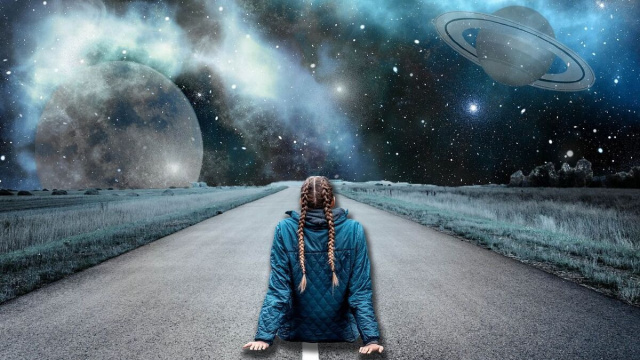 Una ragazza seduta sulla strada osserva lo spazio © Pixabay.