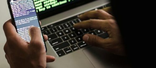 Persona inserisce codici informatici da pc e smartphone © Pexels