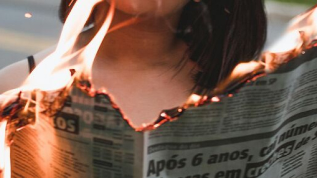 Donna che legge un giornale che brucia © Pexels