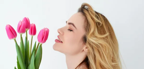 Una donna che annusa dei fiori, simbolo di primavera © Immagine Pexels