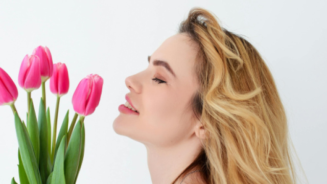 Una donna che annusa dei fiori, simbolo di primavera © Immagine Pexels
