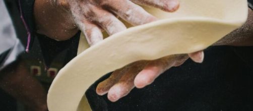 Mani che preparano una pizza © Pexels.com