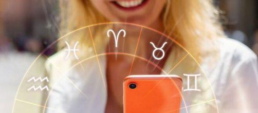 Donna con telefono e ruota dei segni zodiacali © Pixabay.